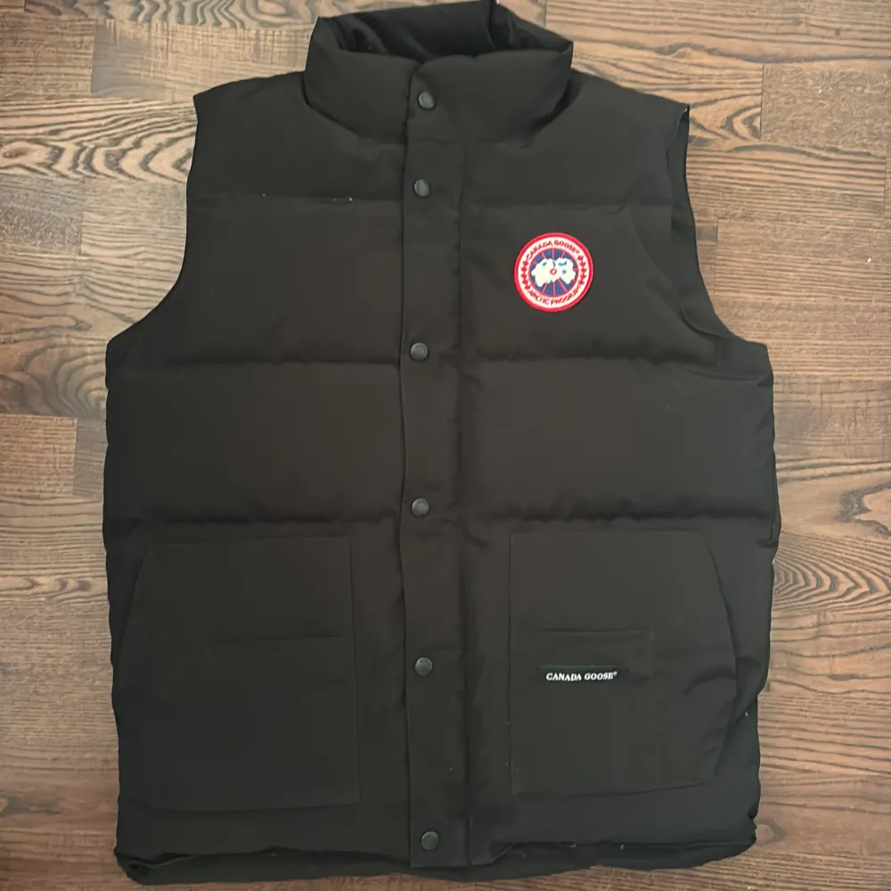 Svart canada goose väst i otroligt bra skicka helt ny har bara testat har inte tagit på mig den då jag köpte den för tidigt i sommar och tröttnat på den, västen har Scan och fler bilder kan skickas ifall det behövs storlek:L Passar också m 1:1K. Jackor.