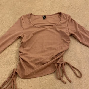 Beige ribbad topp med knyt - Säljer en beige ribbad topp med långa ärmar och knytband i sidorna. Perfekt för en stilren look. I storlek s, men passar för xs och xss också!😊