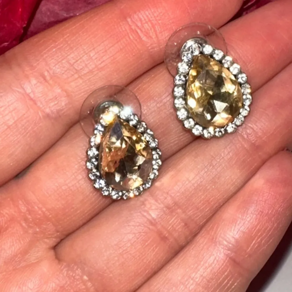 Snygga droppformade örhängen i guld med glittrande stenar runtom. Perfekta för att ge en elegant touch till din outfit. De har en klar och skimrande finish som fångar ljuset vackert.. Asusteet.