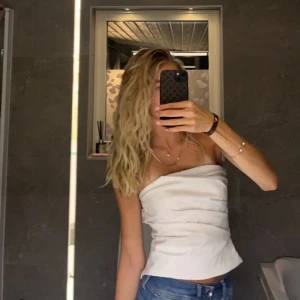 Vit topp - Snygg vit axelbandslös topp med en stilren design. Perfekt för varma sommardagar eller en kväll ute. Sitter jättefint och är bekväm!