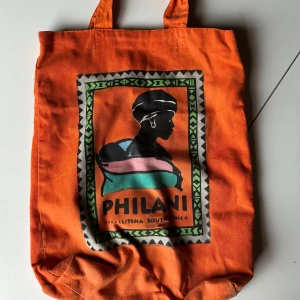 Orange tygkasse - Tygkasse använd flitigt för många år sen, bara legat sedan dess. Mycket vackert tryck gjort av kvinnor i Afrika. 