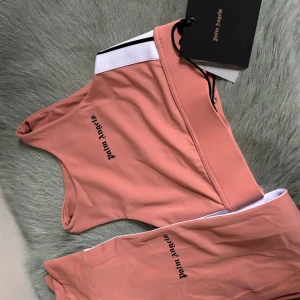  Palm Angels - Snyggt tränings sett från Palm Angels med svart text på sidan. De har en vit och svart rand längs byxans sida som ger en sportig look. Perfekta för en avslappnad stil och träning. ”Sport-bh/topp och tights” pris kan diskuteras! Äkta köpta på nk 