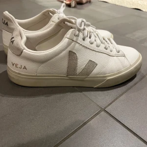 Vita sneakers från Veja - Snygga vita sneakers från Veja med klassisk design och snörning. Skorna har en diskret logga på sidan och är tillverkade i skinn. Perfekta för en stilren look. Använda endast en gång. Ny pris ca 2000kr