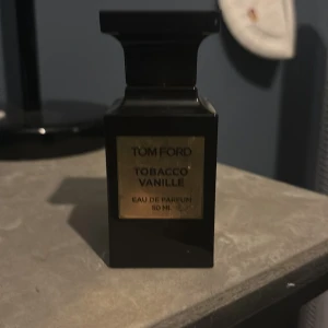 Tom Ford Tobacco Vanille Eau de Parfum - Elegant och lyxig parfym från Tom Ford, Tobacco Vanille, i en stilren svart flaska. Doften kombinerar rika noter av tobak och vanilj, vilket ger en varm och kryddig upplevelse. Flaskan rymmer 50 ml och är perfekt för den som söker en sofistikerad och unik doft.