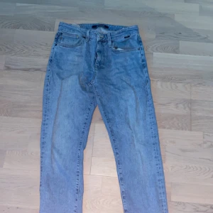 Blå jeans från Mavi - Snygga blå jeans från Mavi med klassisk femficksdesign. De har en slim tapered passform och är perfekta för en avslappnad stil. Jeansen har en dragkedja och knapp framtill. Bred runt om midjan och blir smalare när man kommer till fotleden. Säljer denna eftersom den nu är för liten för mig. 