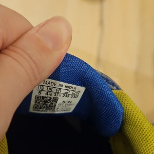 Blå sneakers från Adidas - Säljer ett par blå sneakers från Adidas med gula detaljer och kardborreband. Skorna har en vit sula och är perfekta för en sportig look.