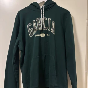 Mörkgrön hoodie från Garcia - Snygg mörkgrön hoodie från Garcia. Den har en klassisk passform med långa ärmar och en bekväm huva med dragsko. Den är enbart testad. För referens är jag 183cm och väger 81kg 