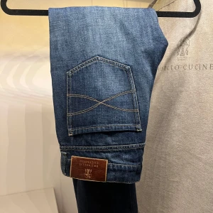 Brunello Cucinelli Jeans - Säljer ett par blåa jeans från Brunello Cucinelli med knappgylf och klassisk femficksdesign. Perfekta för en stilren look med högkvalitativt material och detaljerad sömnad. Helt nya med lappar kvar. Nypriset ligger på 8.699kr. Dm för frågor eller fler bilder.