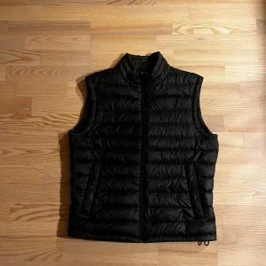 Hugo Boss Väst - Superfin väst från Hugo Boss i storlek M. Bra skyddande mot kyla under de kallare månaderna och sitter jättebra. Har fickor på sidorna och en innerficka samt är justerbar i midjan. Säljer då den blivit för liten
