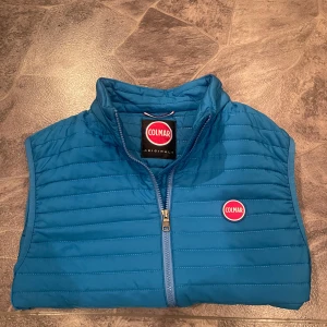 Unik väst från Colmar - Säljer en snygg blå quiltad väst från Colmar med dragkedja och två praktiska fickor framtill. Perfekt för lager-på-lager under kyliga dagar. Västen har en stilren design med Colmar-logga på bröstet. Västen är i toppskick och har inga tecken på defekter eller liknande. Priset kan diskuteras, hör av er vid frågor eller liknande😊