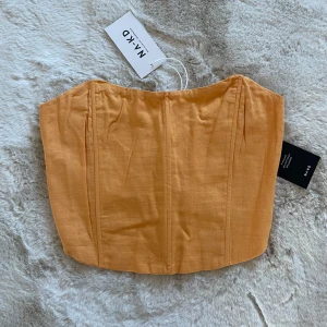 Orange korsettopp från NA-KD - Trendig orange korsettopp från NA-KD i ett stilrent och enkelt utförande. Toppen har en smickrande passform och är perfekt för att lyfta din outfit. Den är tillverkad i ett lätt och bekvämt material.