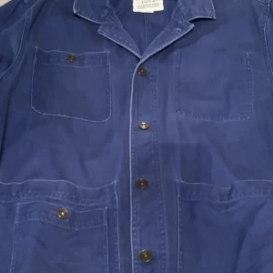 Dal denim jacket är en jeansjacka från varumärket Dobber  - DAL DENIM JACKET Dal denim jacket är en jeansjacka från varumärket Dobber i delvis återvunnen bomull. Den stängs med donut-knappar fram och har bröstficka samt två fickor nedtill på framsidan. Jackan har krage och dekorativa sömnadsdetaljer fram och vid ärmslut. Passformen är rak.  Genom att köpa bomullsprodukter från MarQet, stöder du mer hållbart odlad bomull.  Artikelnummer: 1231204