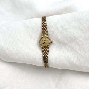 Desirée -Elegant guldfärgad klocka - Klockan Desirée är en snygg guldfärgad klocka från märket Leijona med klassisk design och länkarmband. Perfekt accessoar för att lyfta din stil. Klockan har en rund urtavla och ett smidigt spänne för enkel justering. - Omkrets: 16,8cm Urets bredd: 1,5cm Längd: 18cm