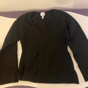 Svart v-ringad tröja - Snygg svart tröja med v-ringning och långa ärmar. Tröjan har ribbade muddar vid ärmslut och nederkant, från hm. Endast använd 1 gång. 