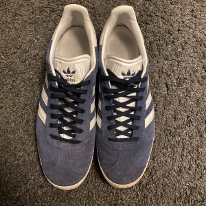 Blå Adidas Gazelle sneakers - Blå Adidas gazelle skor i storlek 45. Skorna har endast blivit andvända några enstaka gånger men säljer dem för att storleken är fel. Skorna är köpta på Zalando.