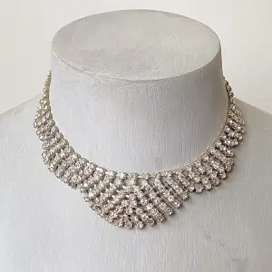 Säljer ett superglittrigt halsband med massor av strass som verkligen fångar ljuset. Det har en vacker, flätad design som ger en lyxig känsla. Perfekt för fest eller nyår! Halsbandet är justerbart med en kedja och ett enkelt lås i bak.