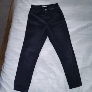Svarta jeans från Gina Tricot - Säljer ett par svarta jeans från Gina Tricot i storlek 34. De är högmidjade och har en klassisk femficksdesign med knapp och dragkedja framtill. Perfekta för både vardag och fest!