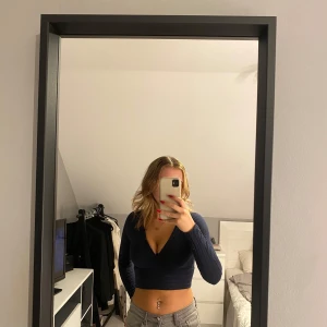 Mörkblå croppad topp från Shein - Säljer en snygg mörkblå croppad topp från Shein. Den har en djup v-ringning och långa ärmar, perfekt för en kväll ute eller en fest. 