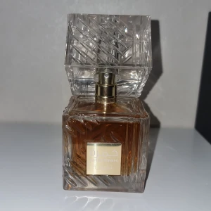 Khamrah Eau de Parfum från Lattafa - Säljer en lyxig parfymflaska från Lattafa, Khamrah Eau de Parfum. Flaskan är elegant med ett snyggt mönster i glaset och en gyllene etikett. Den har en fyrkantig form och rymmer 100 ml av en doft som är både mystisk och förförisk. Perfekt för speciella tillfällen eller när du vill känna dig extra speciell. Kommer i en stilren svart och guld förpackning.