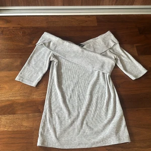 Grå offshoulder klänning från Gina Tricot - Säljer en superfin grå offshoulder klänning från Gina Tricot. Den är ribbad och har trekvartsärm, perfekt för både vardag och fest. Klänningen är i ett mjukt och bekvämt material som sitter snyggt på kroppen. Passar perfekt till höst och vår! 🥰🥰