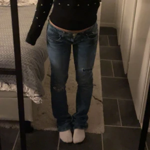 Ltb Blå jeans med slitningar  - Säljer ett par blå jeans med slitningar på knäna. De har en låg midja och en bootcut-stil som ger en avslappnad look. Perfekta för en casual outfit. Storlek W28 L33 men passar mig som har W26-W27. Dom är några cm för långa för mig som är 162😊