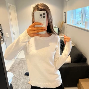 Vit stickad tröja - Säljer en stilren vit stickad tröja med rund halsringning från vila Tröjan har långa ärmar och ribbade muddar vid ärmslut och nederkant. Perfekt för kyligare dagar.