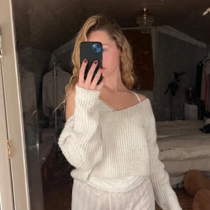 Vit stickad offshoulder tröja - Säljer en mysig vit stickad tröja med offshoulder-design. Tröjan är croppad och har långa ärmar, perfekt för en avslappnad stil.