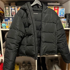 Balenciaga Cropped Puffer - Säljer en svart pufferjacka från Balenciaga. Jackan har en quiltad design med en dragkedja framtill och en huva. Perfekt för kyligare väder och ger en stilren look. Den är cropped i design. Skickar fit pic vid förfrågan