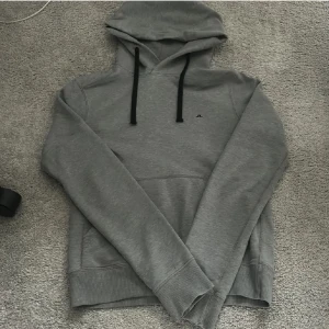 Grå hoodie från J.Lindeberg - Säljer en skit snygg grå hoodie från J.Lindeberg. Hoodien har inga defekter alls och skicket är som nytt. Storleken är S.  Hör av dig vid mer frågor!