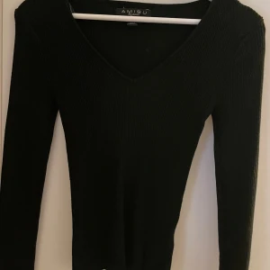 Svart ribbad tröja - Snygg svart ribbad tröja från newyorker med v-ringning. Tröjan har långa ärmar och är i en bekväm passform.
