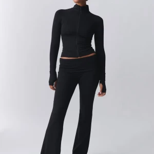 Svart tight tröja med dragkedja oanvänd  - Snygg svart tight tröja med dragkedja framtill. Perfekt för en stilren look. Tröjan har långa ärmar och en hög krage.