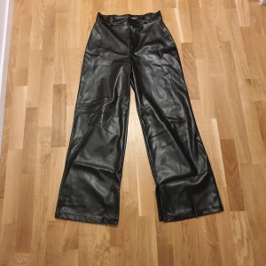 Svarta skinnbyxor  - Aldrig använda!! Snygga svarta skinnbyxor från Marian Bou Assaf Design köpta utomlands. Hög midja och raka ben. Byxorna har praktiska bakfickor och stängs med knapp och dragkedja framtill. Perfekta för en trendig look! Let's fashion😉 Stl. L men midja skulle jag nog säga M