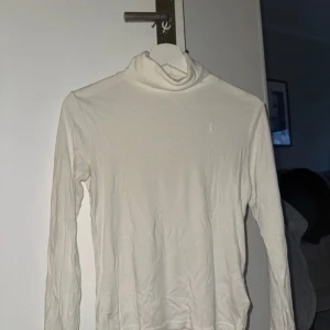 Vit polotröja från Ralph Lauren - Säljer en stilren vit polotröja från Ralph Lauren. Tröjan har långa ärmar och en klassisk polokrage, perfekt för kyligare dagar. Den är i ett mjukt och bekvämt material. Storlek xl (barn)