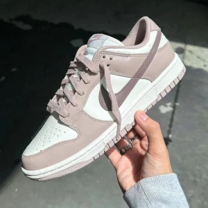Nike sneakers i beige och svart - Två par Nike sneakers. Det första paret är Nike Dunk i beige och vitt med snörning. Det andra paret är Nike Air Jordans i svart och vitt med snörning och den ikoniska loggan på plösen.