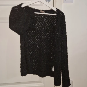 Svart glittrig tröja från Vero Moda - Snygg svart glittrig tröja från Vero Moda. Perfekt för att lägga till lite glamour i din garderob. Tröjan har långa ärmar och en bekväm passform.