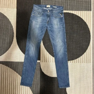 Replay Anbass - Snygga blå jeans från Replay med en klassisk femficksdesign och knappgylf. De har en lätt tvättad look och är perfekta för en avslappnad stil. Märkesdetaljer syns på fickan och baksidan. Pris inte hugget i sten!