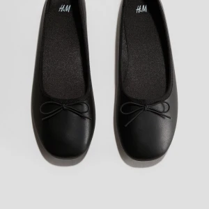 Svarta ballerinaskor från H&M - Stilrena svarta ballerinaskor från H&M med en söt rosett på ovansidan. Perfekta för en enkel och elegant look. Helt nya, skickas samma dag eller dagen därpå! Helt slutsålda💗strl. 37 men något stora i storleken 