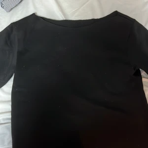 Svart kortärmad topp - En stilren svart kortärmad topp i mjukt material. Perfekt för en enkel och klassisk look. En avklippt sweatshirt till T-shirt 