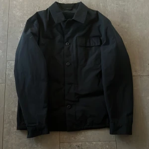 Svart jacka från Massimo Dutti - Snygg svart jacka från Massimo Dutti i storlek L. Jackan har en klassisk design med knappar framtill och en bröstficka. Perfekt för en stilren look.