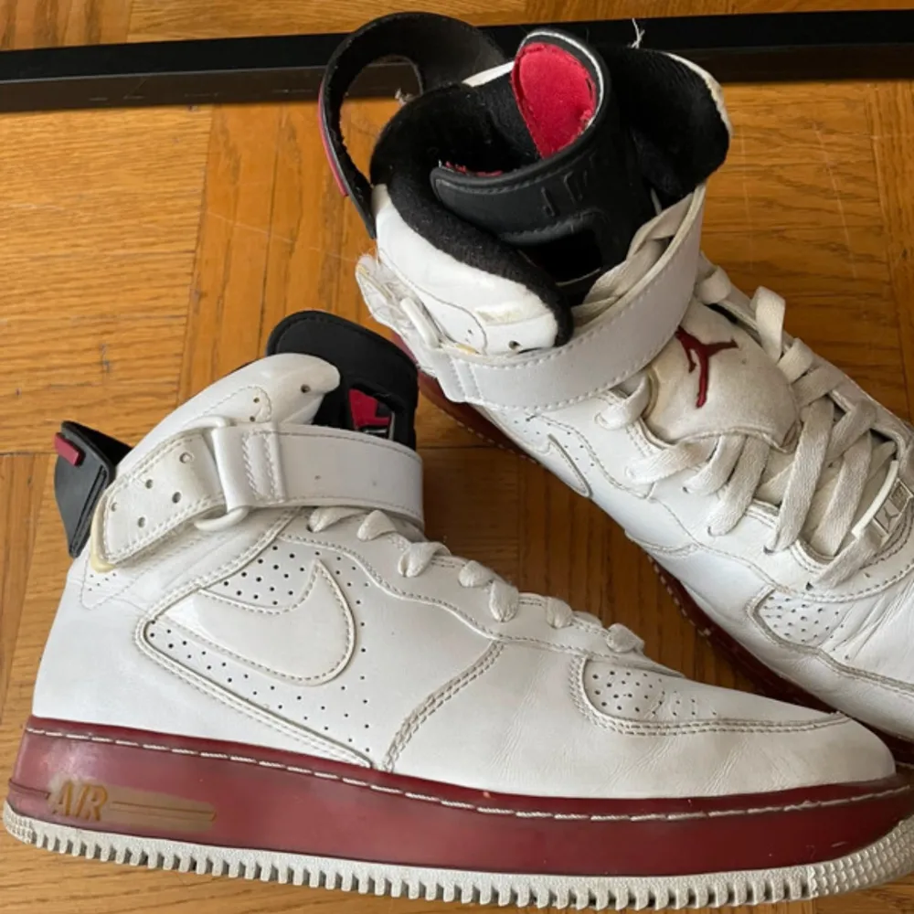 Snygga Nike Air sneakers i vitt med röda detaljer. Skorna har snörning och en hög design med den klassiska Air-loggan på hälen. Perfekta för en sportig look.. Kengät.