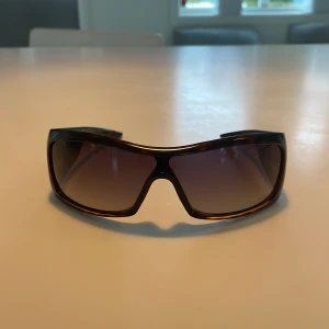 Äkta Dior Solglasögon - Snygga solglasögon från Dior med en bred båge i leopardmönster. Glasen är tonade och ger ett coolt intryck. Perfekta för att ge din stil en lyxig touch.