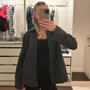 Mörkgrå jacka med dragkedja - Säljer en stilren mörkgrå jacka med dragkedja framtill. Jackan har en normal passform och långa ärmar, perfekt för höst och vår. Enkel och snygg design som passar till många olika outfits. Den är i fint skick 