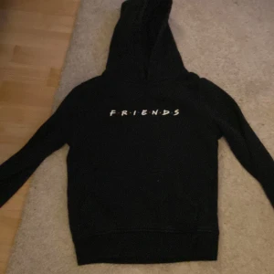 Svart hoodie med Friends-tryck - Säljer en svart hoodie med luva med Friends-trycket på bröstet. Den är i strl 146/152.