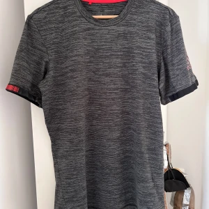 Grå t-shirt från Adidas storlek S som ny! - Snygg grå t-shirt från Adidas med diskret mönster och logga på ärmen. Perfekt för träning eller vardagsbruk. Kortärmad design med bekväm passform.
