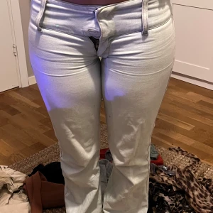 Ljus blå jeans med bootcut - Snygga vita jeans med bootcut och låg midja. Perfekta för en stilren look. De har en klassisk design med knappar och dragkedja framtill.