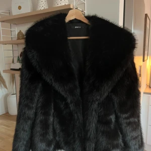 Svart fluffig pälsjacka från gina tricot - Kort pälsjacka med stor krage.  Jackan är svart och har mjuk, fluffig kvalitet. Den har oversize fit, lång ärm, hysk- och hakestängning framtill och fickor i sidorna 🖤🖤 Jackan är använd nyskick max 1 använd ❤️
