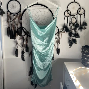 Mintgrön sidenklänning - Snygg mintgrön klänning i siden med smala axelband och draperad design. Perfekt för en elegant look med sin glansiga finish och figurnära passform.