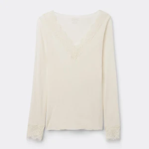 Vit långärmad topp med spetsdetaljer - Elegant vit långärmad topp med v-ringning och spetsdetaljer vid hals och ärmslut. Perfekt för en stilren look. Säljs pga att jag inte använder så mycket!