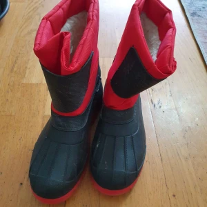 Svart och röd vinterstövlar - Säljer ett par robusta vinterstövlar i svart och rött. De är fodrade för extra värme och har en slitstark sula. Perfekta för kalla vinterdagar. Tillverkade i Italien.