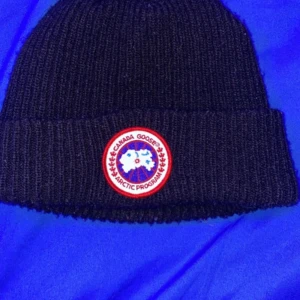 Canada goose mössa - Canda goose mössa, har använt 10-15 gånger, det finns ett litet hål på toppen av mössan men syns ej när man har på sig den och märks ej om man letar efter hålet, den är lite smutsigt, kan göra rent den om du vill, pris kan diskuteras men kräver 400